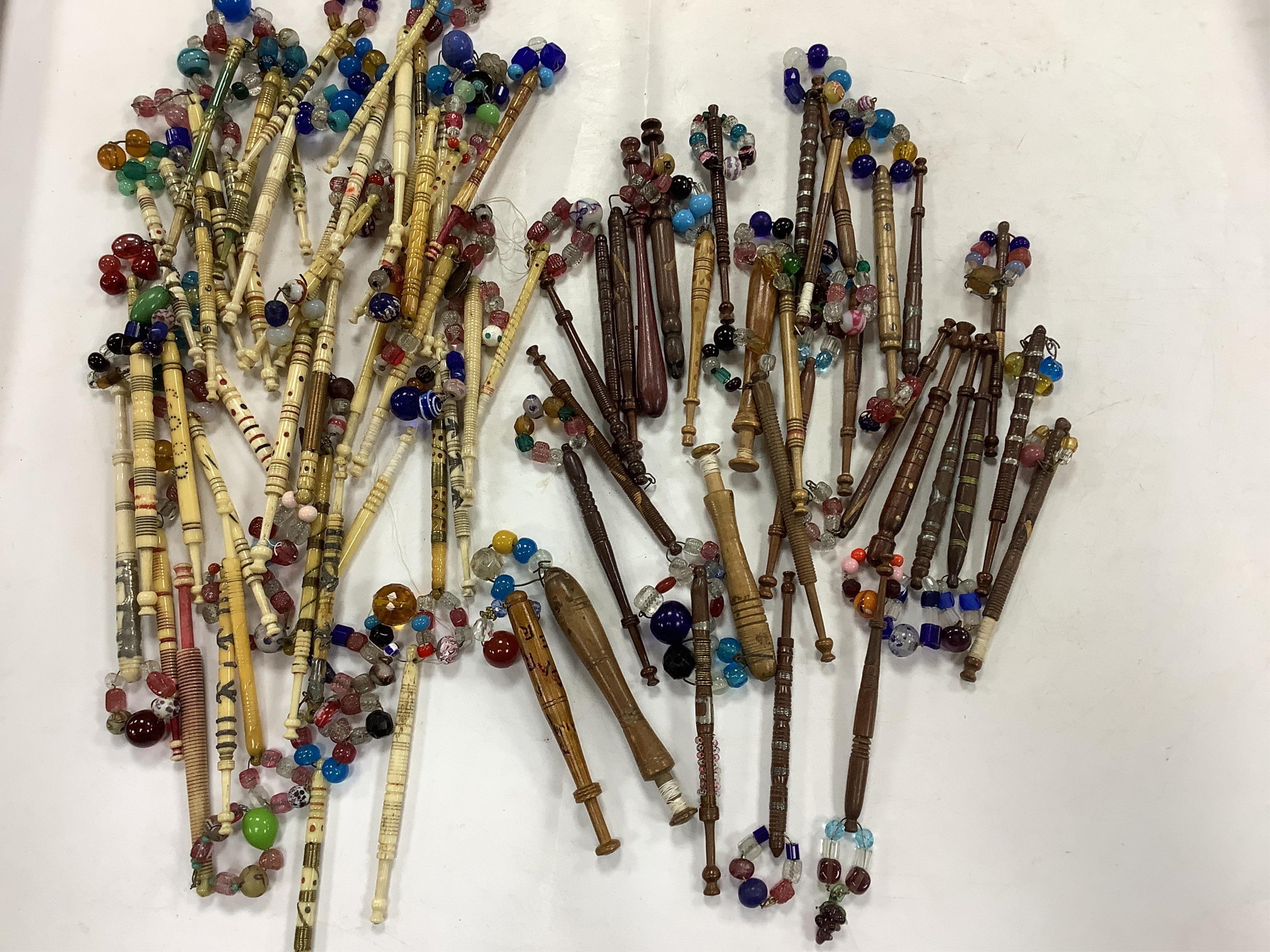 A collection of mostly 19th and 20th century ornate bone lace making bobbins, with coloured beaded ends, together with a similar smaller selection of wooden bobbins. Condition - good